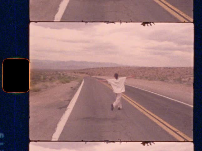 Young woman dances across a deserted highway, on Super 8 film
