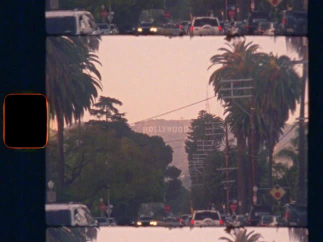 Zoom in on the iconic Hollywood sign from a palm tree-lined street in Los Angeles, on nostaligc Super 8 film