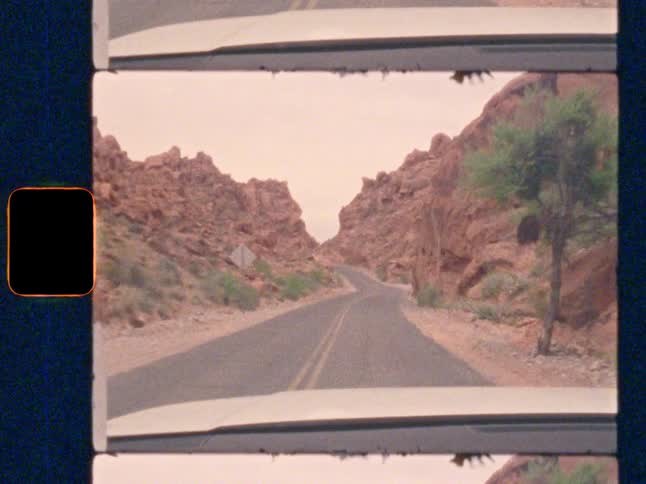 POV driving through a red rock canyon with a smiling young woman, on Super 8 film