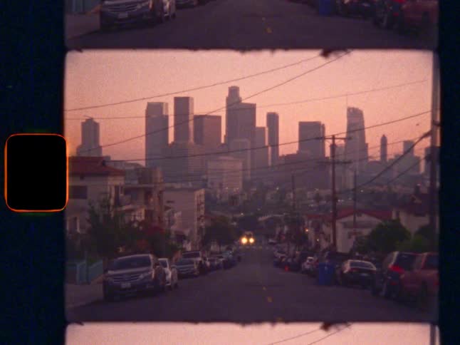 Slow zoom out to reveal iconic Los Angeles skyline at sunset, on Super 8 film