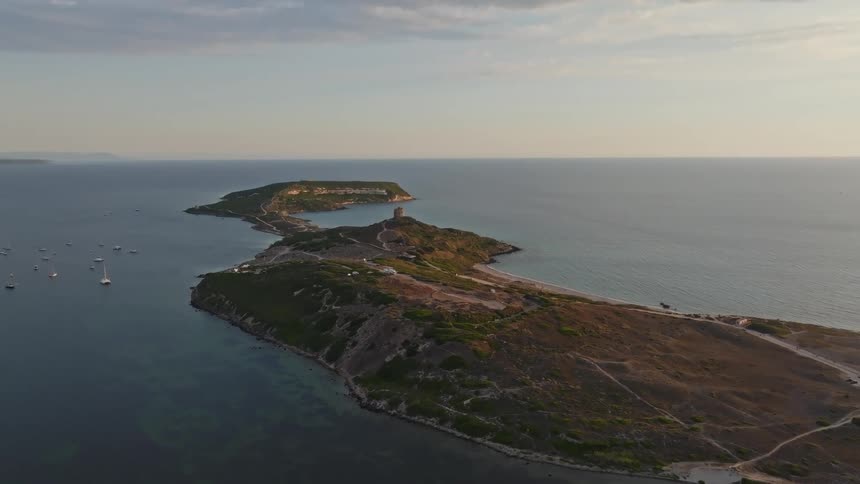 An aerial view shows the beautiful Capo San Marco peninsula and its historic tower in Sardinia, Italy, during a golden sunset