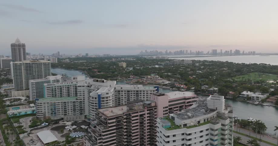 A slow aerial push-in shot over the high-rise hotels of Miami Beach, with the Intracoastal Waterway and the distant city skyline