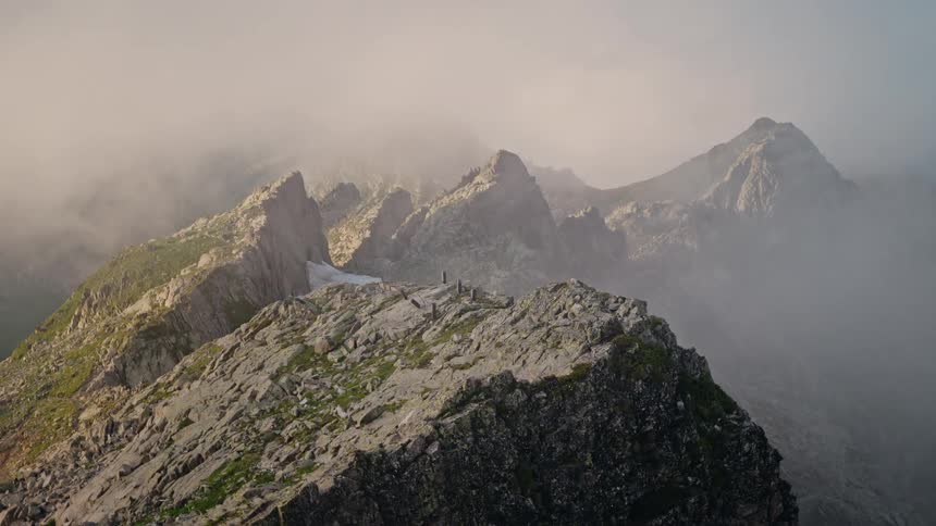 A majestic view of a rocky mountain ridge with peaks emerging through a thick blanket of fog