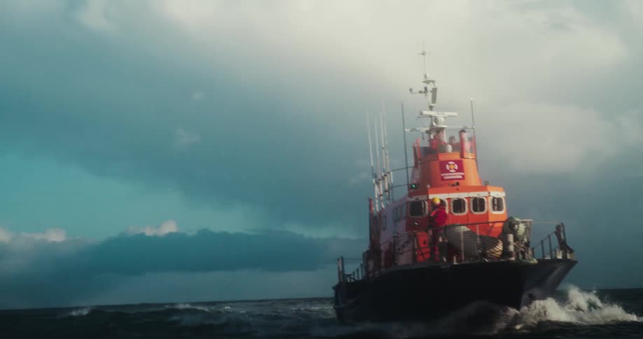 A slow-motion tracking shot follows an Icelandic search and rescue lifeboat as it navigates the choppy ocean with its crew on deck