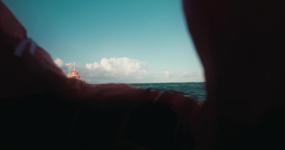 Point of view from a life raft as a coast guard rescue boat sails on the choppy open ocean