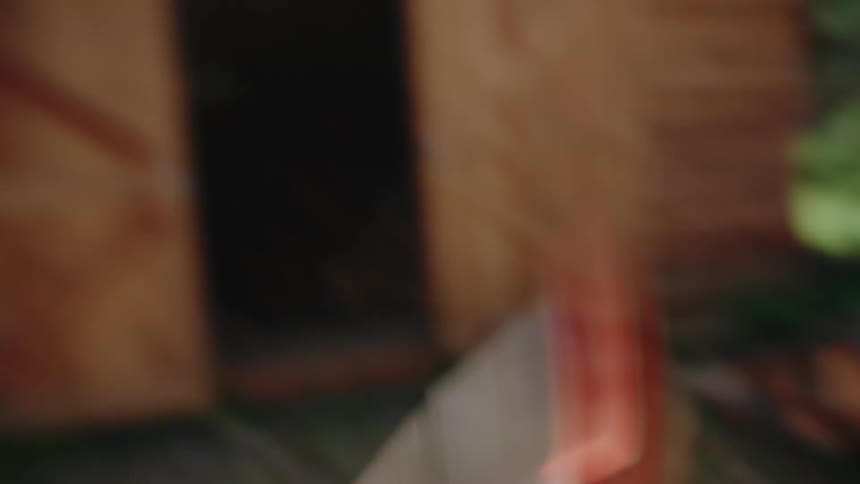 Close-up slow motion shot of a young woman energetically splitting firewood with an axe in the woods
