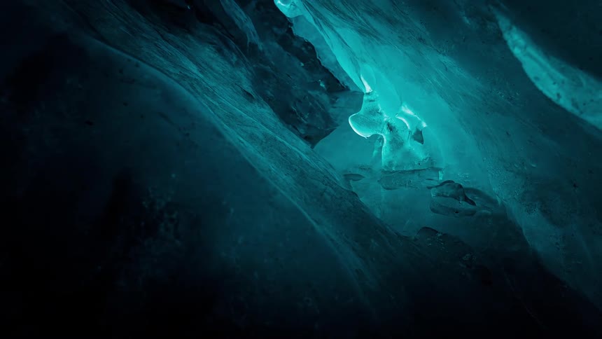A slow, mysterious pull-back shot reveals the shimmering, turquoise blue walls of an ancient ice cave