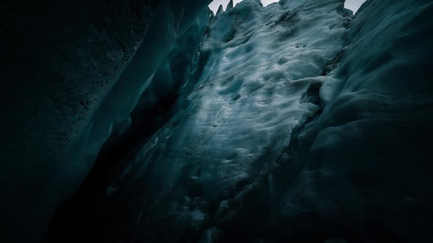 A dramatic timelapse captures clouds moving across the sky from a low-angle perspective deep within a glacial ice cave
