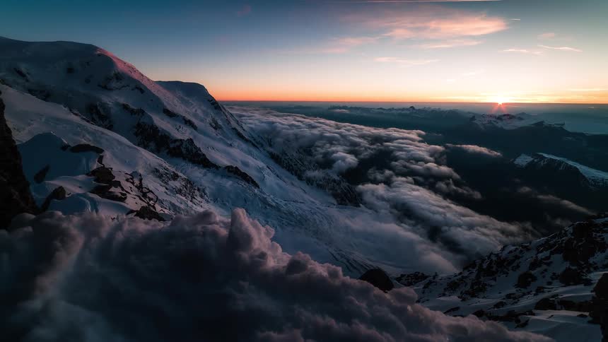 A stunning sunset timelapse from a high mountain peak reveals a vast sea of clouds as the snow turns pink in the fading light
