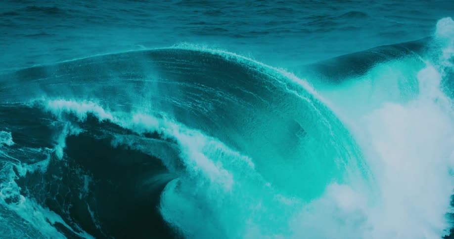A powerful turquoise ocean wave curls in dramatic super slow motion