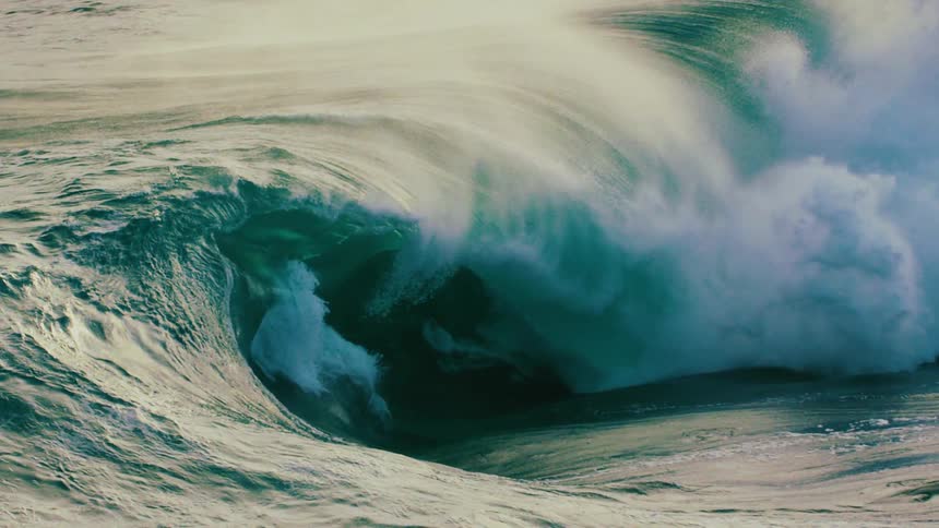 A majestic ocean wave builds and curls into a perfect barrel before crashing in dramatic slow motion