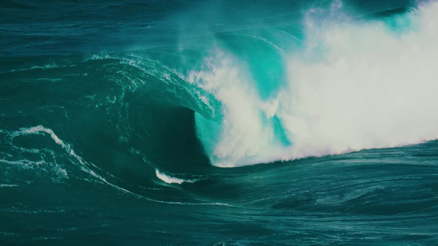 A massive turquoise ocean wave builds and crashes in dramatic super slow motion