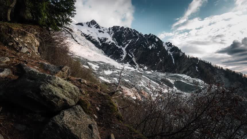 A dramatic time-lapse of clouds moving over a majestic snow-covered mountain and glacier in the Alps