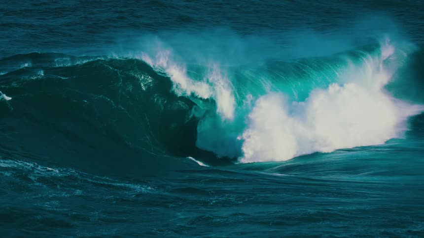 A giant turquoise ocean wave builds, curls, and crashes with immense power in breathtaking slow motion