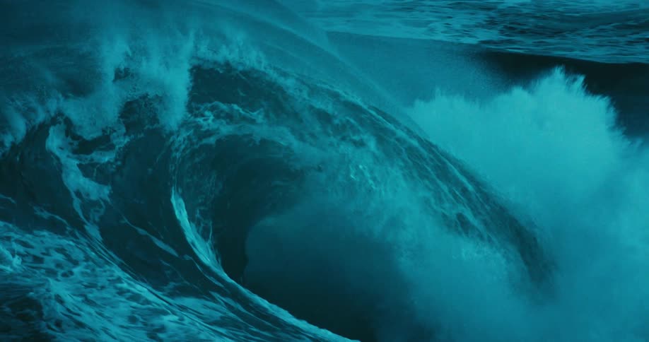 A dramatic slow-motion close-up of a powerful turquoise ocean wave curling and crashing