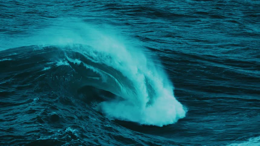 A powerful turquoise ocean wave curls and crashes in dramatic slow motion, showcasing the raw energy of the sea
