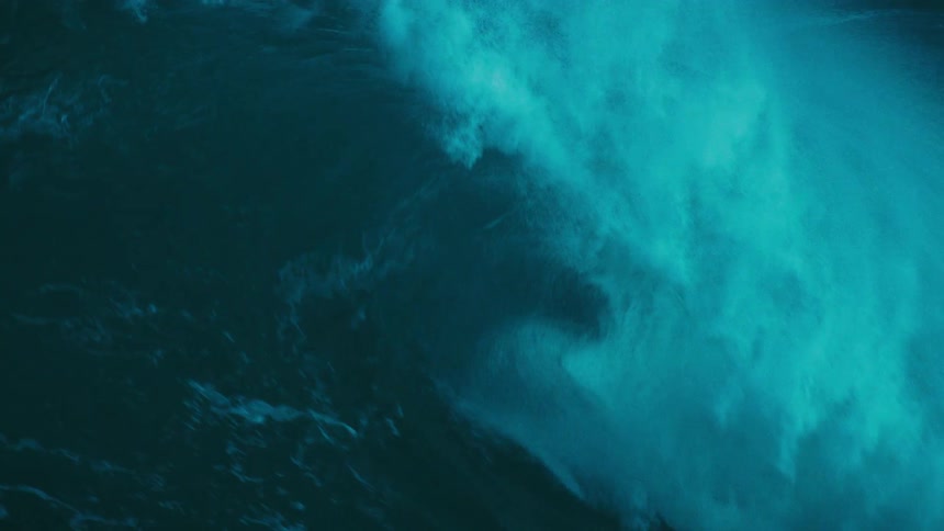 A powerful and mesmerizing slow-motion close-up of a massive turquoise ocean wave crashing