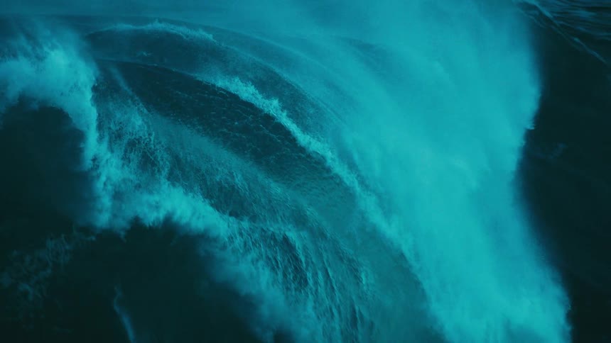 Dramatic super slow motion close-up of a massive, dark turquoise ocean wave cresting