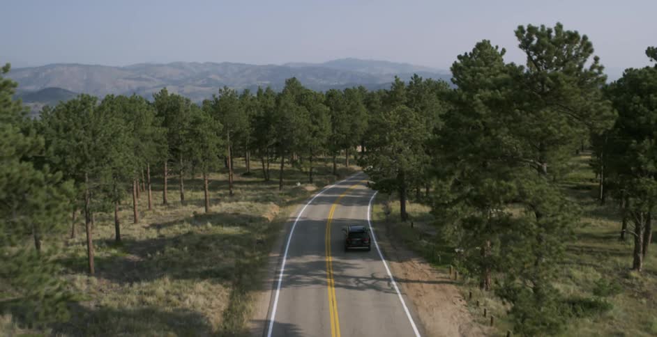 Car traveling on a highway surrounded by trees and mountains