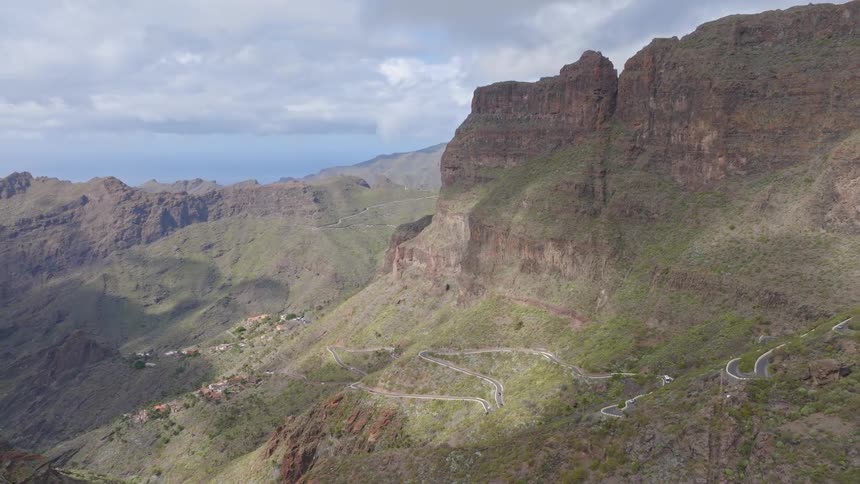 An aerial view reveals the breathtaking Masca Valley in Tenerife, showcasing the winding mountain road and the remote village nestled in the dramatic landscape