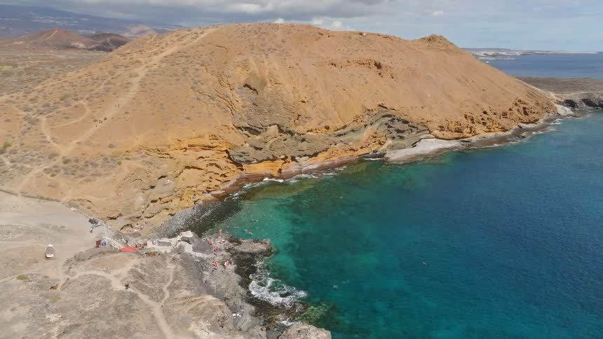Stunning aerial pull-back shot showcases the beautiful Playa Amarilla beach with its turquoise water and unique volcanic landscape in Tenerife