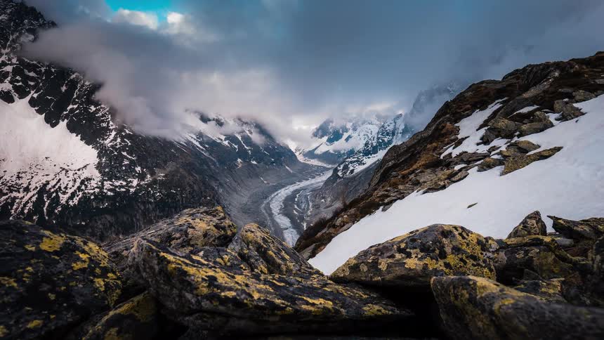 A dramatic timelapse reveals the majestic Mer de Glace glacier winding through the snowy Alps as clouds swirl and dance overhead