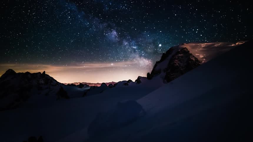 A majestic timelapse of the Milky Way rising over a serene, snow-covered mountain landscape at night
