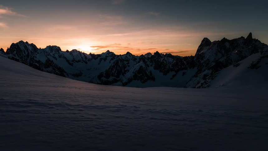 Timelapse of a breathtaking sunrise casting golden light across a serene, snowy mountain vista