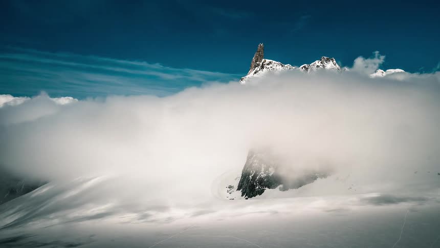 A majestic, snow-capped mountain peak soars above a vast sea of clouds in the serene alpine wilderness