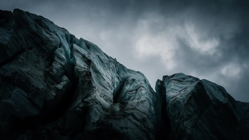A dramatic time-lapse of dark, stormy clouds moving over a massive, frozen glacier