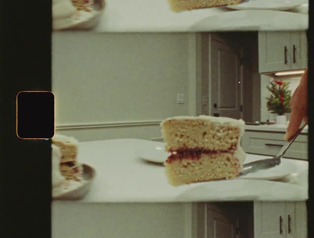 Vintage Super 8 footage captures a hand serving a slice of holiday layer cake with white frosting onto a plate
