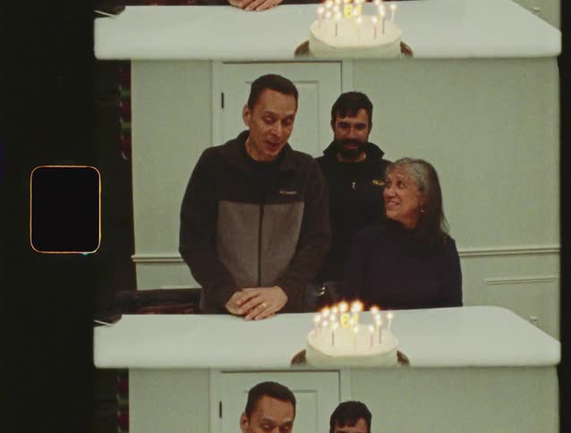 Vintage home movie footage captures a man blowing out the candles for his 61st birthday, surrounded by his family