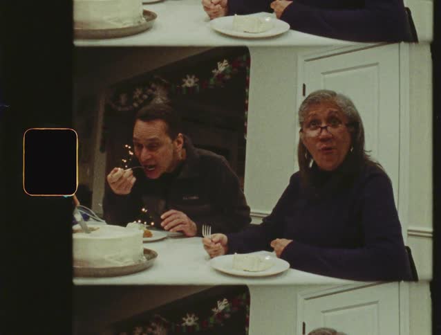 Vintage 8mm film shows a family making funny faces and laughing while eating cake at the dinner table during the holidays