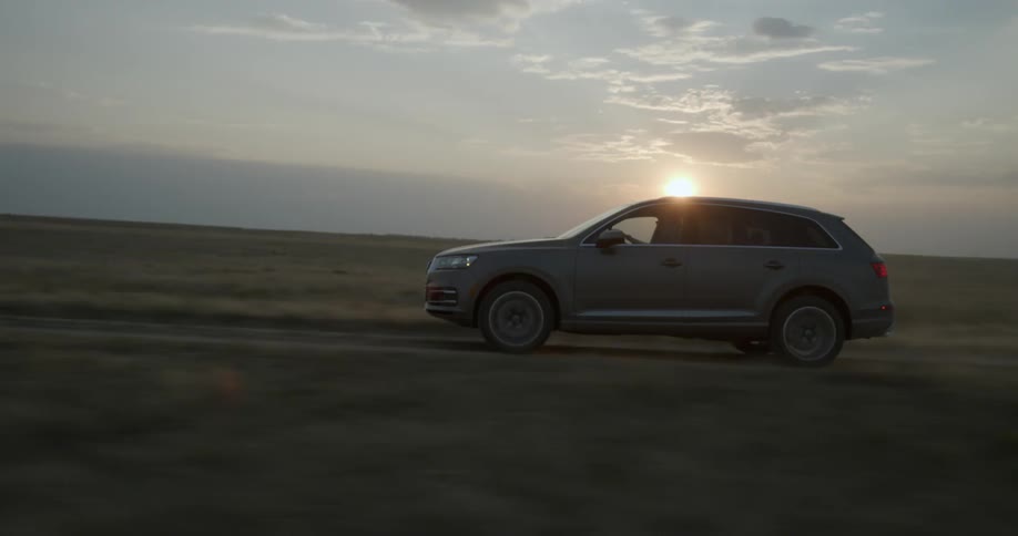 An suv drives in a rural area at sunset
