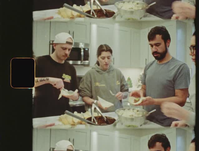 A group of friends and family gathers in a modern kitchen to prepare traditional tamales in this vintage film-style footage