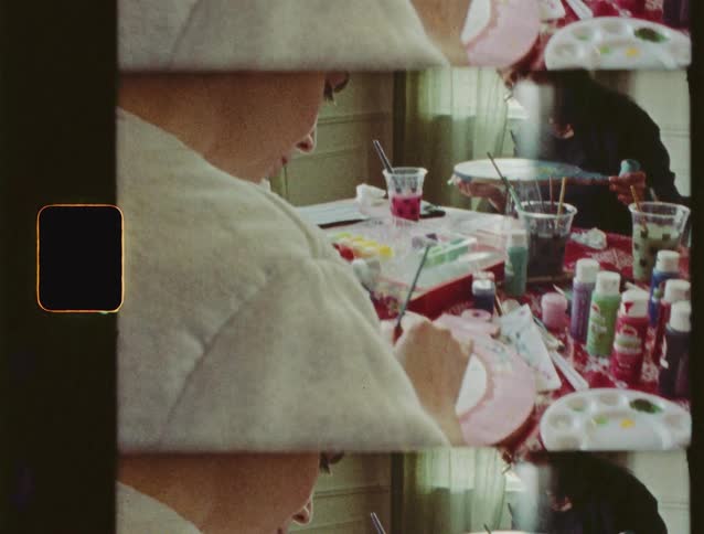 Vintage film shot with a film strip effect shows two women enjoying a creative painting session at a table