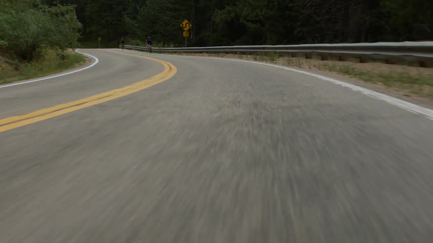 Moving down a winding road past a person riding a bicycle
