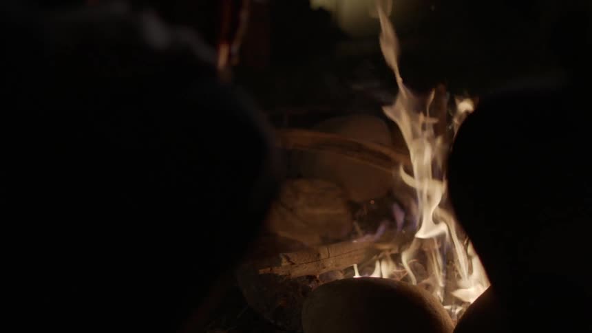 People are pointing sticks into a campfire