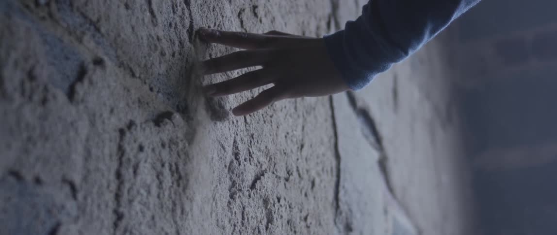 Hand dragging along the side of a building