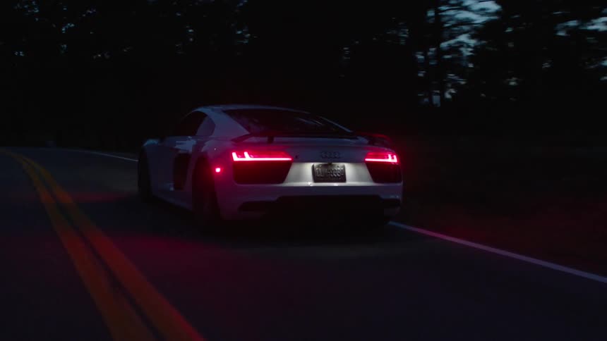 A car moves fast down a road at dawn