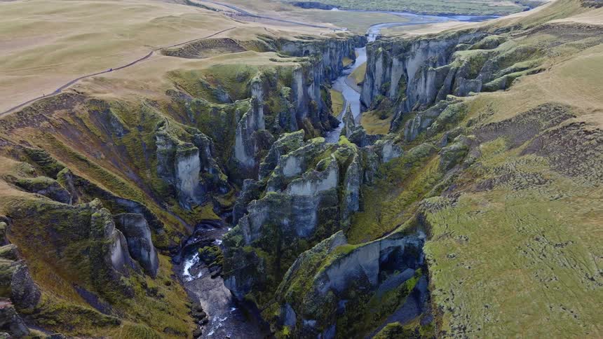 A stunning high-angle aerial view slowly pulls back to reveal the full grandeur of the majestic Fjadrargljufur canyon in Iceland