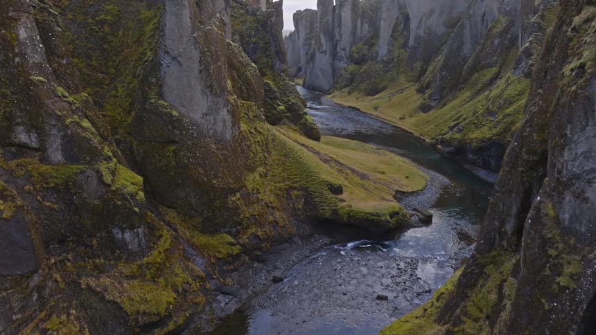 A stunning aerial view reveals the deep and winding Fjaðrárgljúfur canyon in southern Iceland, with a river flowing through its mossy green rock formations