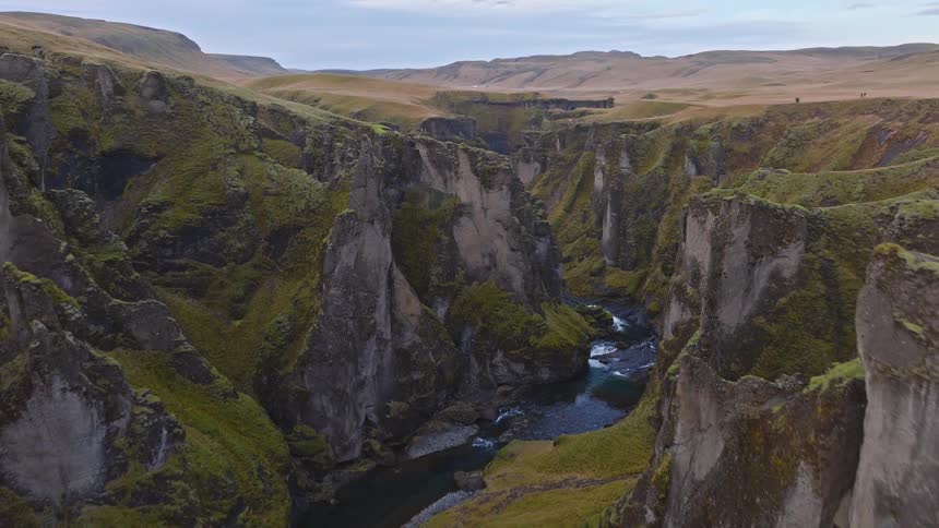 An epic aerial flight through a majestic, moss-covered canyon as a river winds its way through the valley below in Iceland