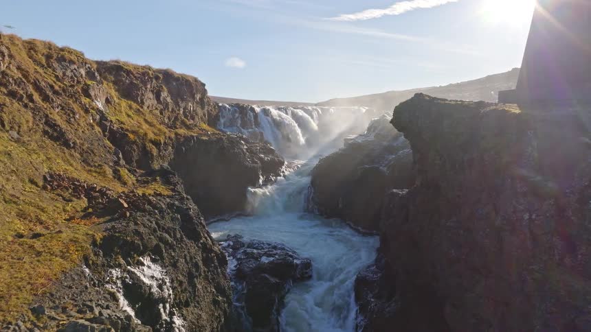 A magnificent view of the Godafoss Waterfall and Skjalfandafljot River rushing through a rugged canyon in Iceland on a sunny day