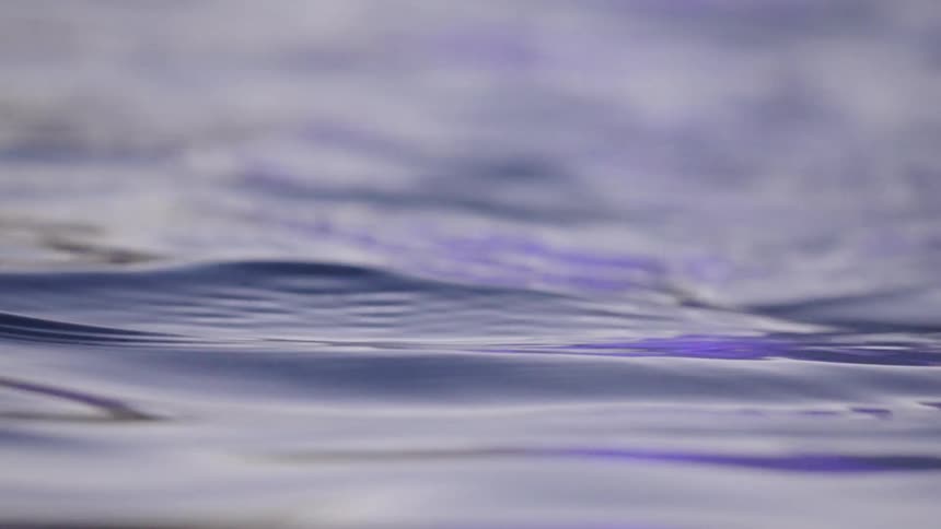 A tranquil close-up of slow-motion purple water ripples gently flowing across the surface