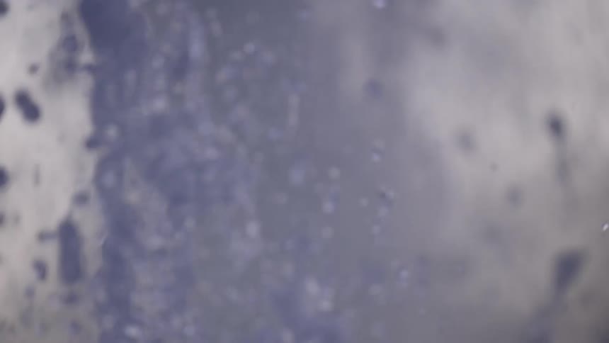 A blurry, abstract close-up of water splashing upwards in super slow motion