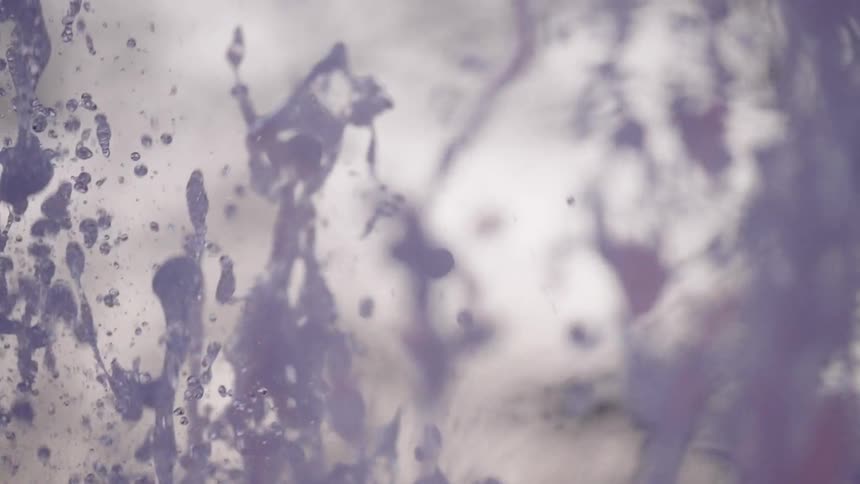 Mesmerizing slow-motion close-up of a purple-tinted water fountain creating beautiful abstract patterns