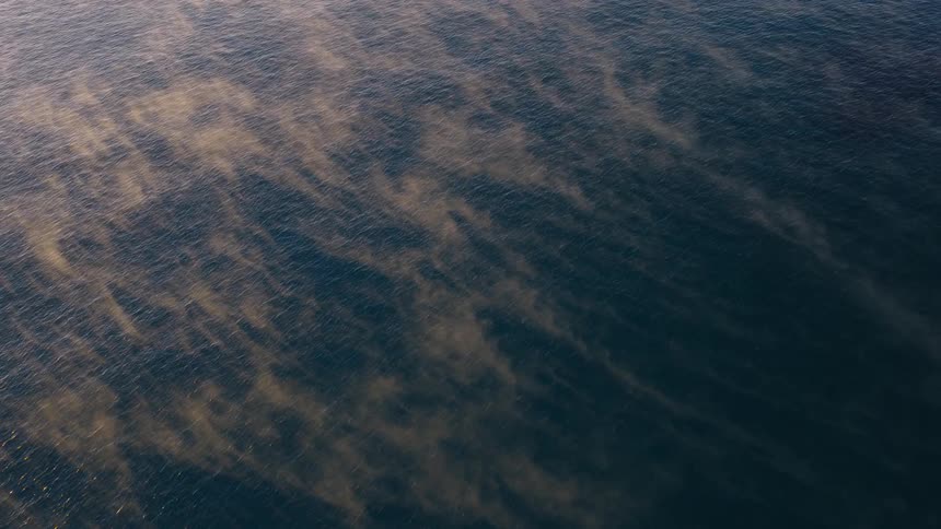 An ethereal top-down view of steam fog rising from the deep blue sea at sunrise