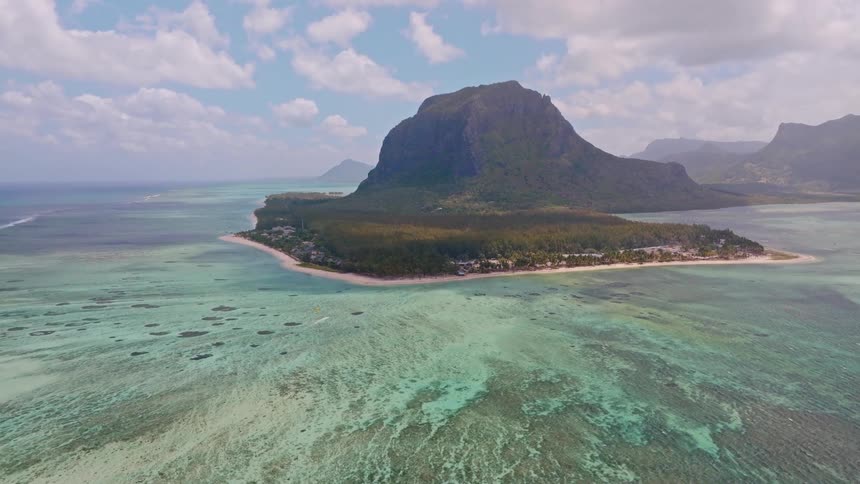 A stunning aerial view of the famous Le Morne mountain in Mauritius, surrounded by a turquoise lagoon that creates the illusion of an underwater waterfall