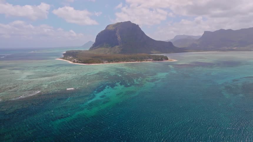 A stunning wide aerial view shows the iconic Le Morne Brabant mountain peninsula and its surrounding turquoise lagoon in Mauritius